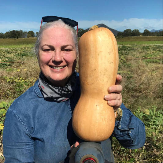 Angela Pennell Certified Organic Farmer in Scenic Rim holding pumpkin on her farm next to her face 