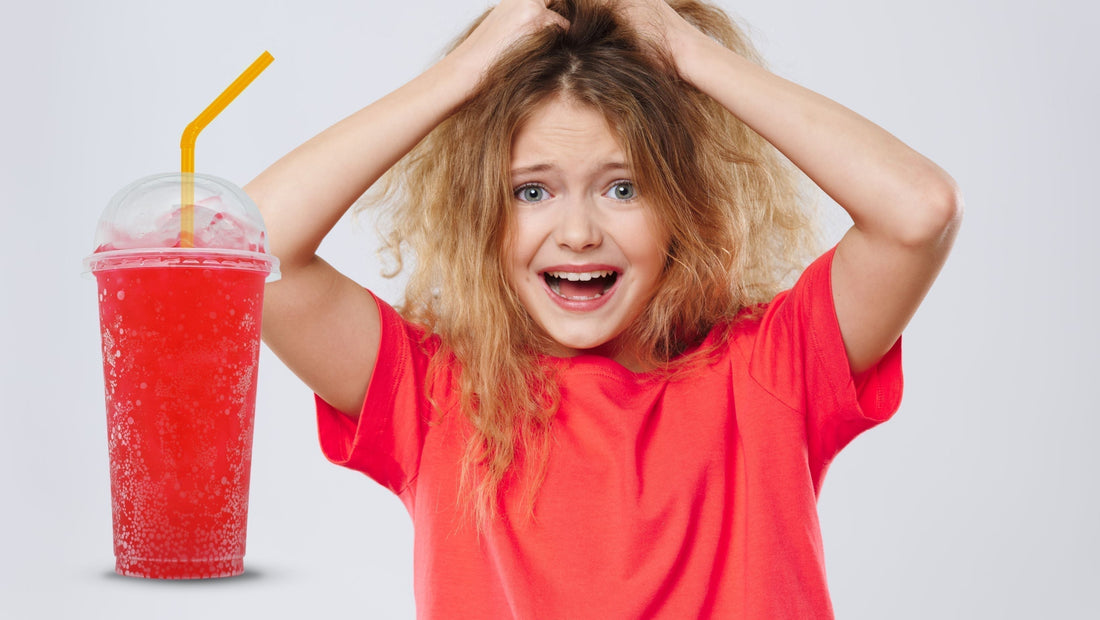 Child pulling hair and looking distressed next to a plastic cup of red coloured icy drink.